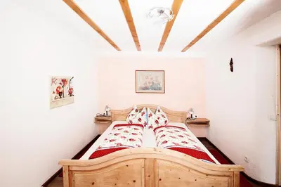a bedroom with a wooden bed with red sheets at Hölzlhof in Brunico