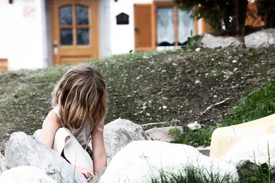 a young child sitting on rocks in front of a house at Hölzlhof in Brunico