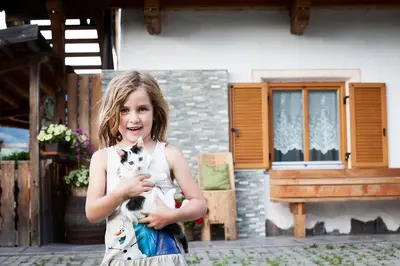 a young girl holding a kitten in front of a house at Hölzlhof in Brunico