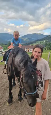 a little girl is sitting on top of a horse at Hölzlhof in Brunico