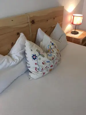 a bed with three pillows on it with a lamp at Grohmann in Campitello di Fassa
