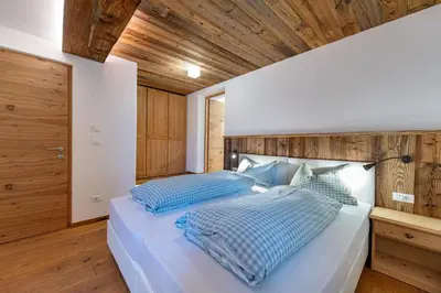 a bedroom with a large white bed with blue pillows at Agriturismo Apartments Tuene in Ortisei