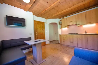 a living room with a table and a kitchen at Agriturismo Apartments Tuene in Ortisei