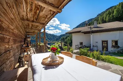 a table with a vase of flowers on a balcony at Agriturismo Apartments Tuene in Ortisei