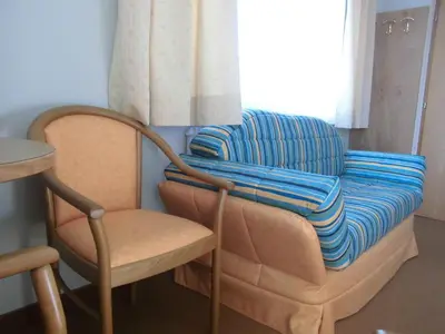 a chair with a blanket on it next to a window at Pension Runer in Terlano