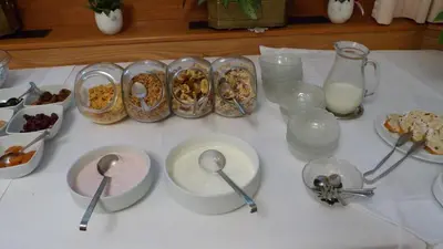 a table with spoons and bowls of food and milk at Pension Runer in Terlano