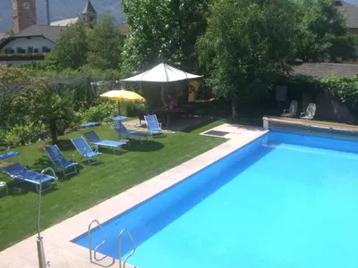 a large swimming pool with chairs and an umbrella at Pension Runer in Terlano
