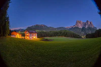 a house on a green field with mountains in the background at Parlunkhof in Castelrotto