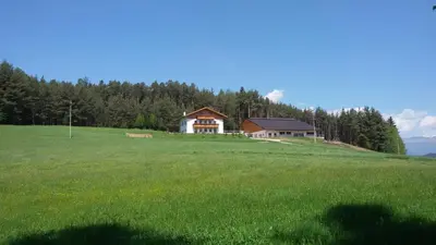 a house on top of a grassy hill with a field at Parlunkhof in Castelrotto