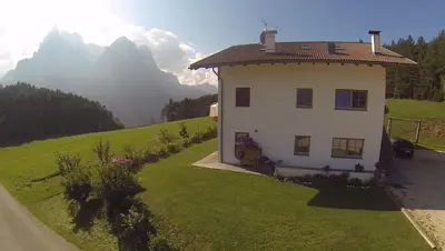 a house in a field with mountains in the background at Parlunkhof in Castelrotto