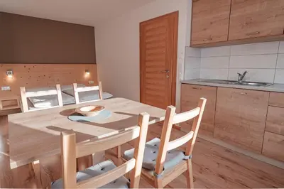 a kitchen and dining room with a wooden table and chairs at Lüch da Morgnun in San Vigilio Di Marebbe