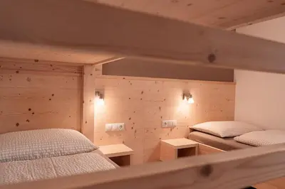 two beds in a room with wooden walls at Lüch da Morgnun in San Vigilio Di Marebbe