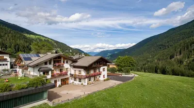 a house on a hill with mountains in the background at Residence Karnutsch in Santa Valburga St. Walburg