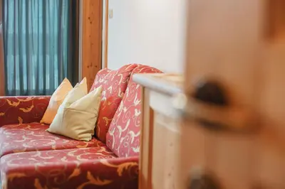 a living room with a red couch with pillows at Residence Karnutsch in Santa Valburga St. Walburg