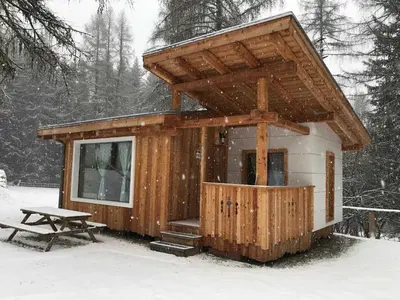 a small cabin in the snow with a picnic table at Club del Sole Val di Fiemme Easy Camping Village in Bellamonte