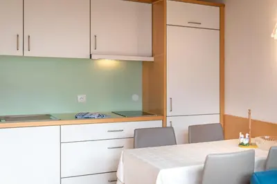 a kitchen with white cabinets and a table and chairs at Haus Piger in Termeno