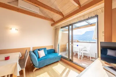 a living room with a blue couch and a large window at Haus Piger in Termeno