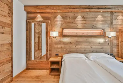 a bedroom with a wooden wall with a bed at Garni Maso San Michele in Cavalese