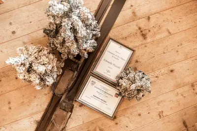 two plants on a wooden floor next to two signs at Garni Maso San Michele in Cavalese