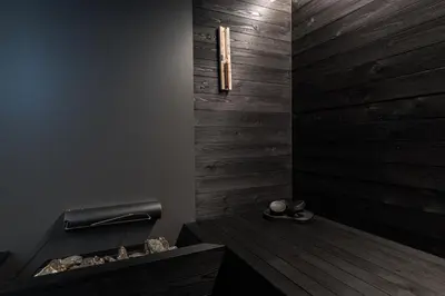 a bathroom with a wooden wall with a bench and a light at Garni Maso San Michele in Cavalese