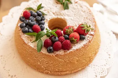 a cake with berries on top of it on a plate at Garni Maso San Michele in Cavalese