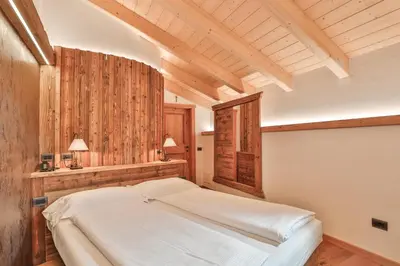 a bedroom with a white bed in a room with wooden walls at Garni Maso San Michele in Cavalese