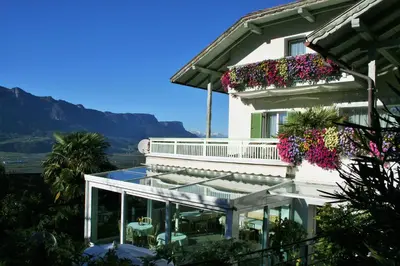 a balcony with a table and flowers and a church at Burgunderhof in Montagna