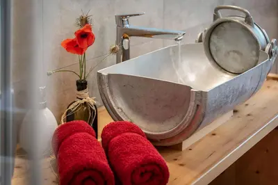 a bathroom sink with red towels on a counter at Platzbon in Bressanone