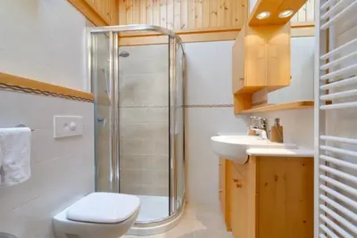 a bedroom with a bed and a wooden cabinet at Appartamento Saslonch 21 in Moena