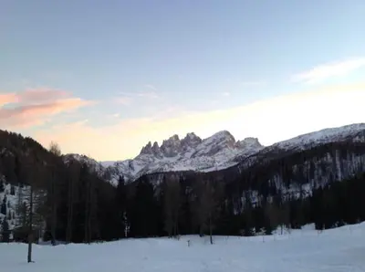 a snow covered field with mountains in the background at Appartamento Saslonch 21 in Moena