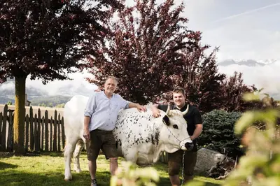two men are standing next to a cow at Hotel Nussbaumerhof *** in Rodengo