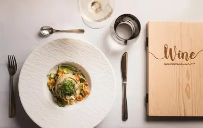 a white plate of food on a table with a book at Hotel Nussbaumerhof *** in Rodengo
