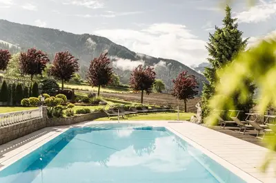 a swimming pool with mountains in the background at Hotel Nussbaumerhof *** in Rodengo