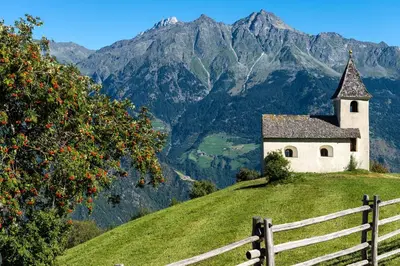 an old church on a hill with mountains in the background at Biohof Niedereben in Rablà