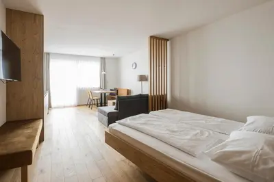 a bedroom with a bed and a living room at Hotel & Residence Rebhof in Tirolo