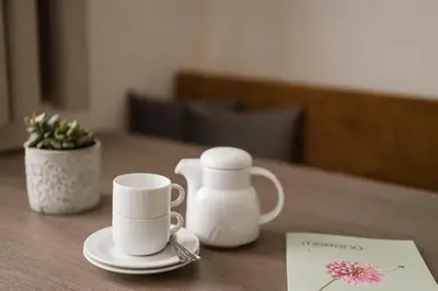 a table with two white coffee mugs and a napkin at Hotel & Residence Rebhof in Tirolo