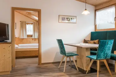 a room with a table and chairs and a bedroom at Hotel & Residence Rebhof in Tirolo