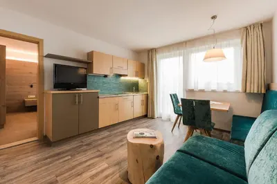 a living room with a couch and a table and a kitchen at Hotel & Residence Rebhof in Tirolo