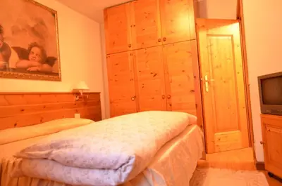 a bedroom with a bed and a dresser and a television at Cá Enrosadira Piano Secondo in San Vito di Cadore