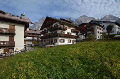 a group of buildings on a hill with mountains in the background at Cá Enrosadira Piano Secondo in San Vito di Cadore