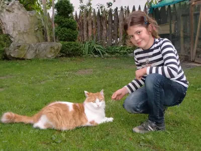 a girl sitting in the grass next to a cat at Appartements Schusterhof in Naz-Sciaves