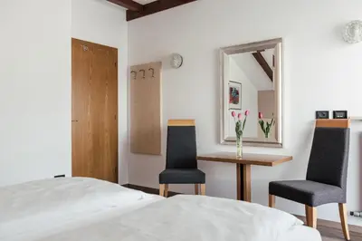 a bedroom with two chairs and a table and a bed at Hotel Garni Sirmian in Merano