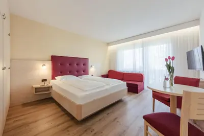 a bedroom with a bed and a table and a couch at Hotel Garni Sirmian in Merano