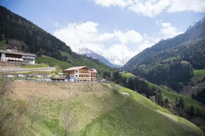 a house on the side of a hill with mountains at Unterer Obereggerhof in San Leonardo in Passiria