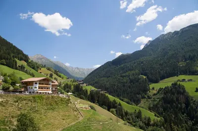 a house on a hill in a valley with mountains at Unterer Obereggerhof in San Leonardo in Passiria
