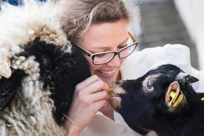 a woman with glasses petting a black sheep at Unterer Obereggerhof in San Leonardo in Passiria