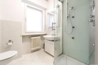a white bathroom with a shower and a sink at Apartment Merano in Merano