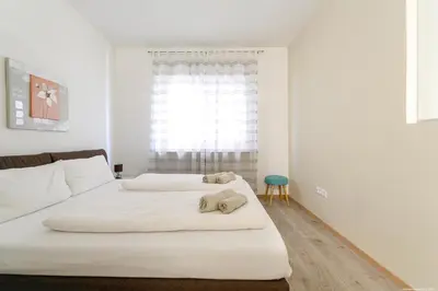 two beds in a white room with a window at Apartment Merano in Merano