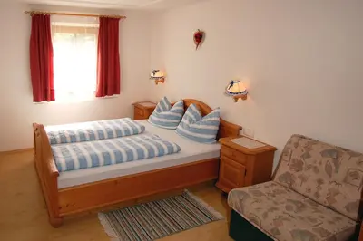 a bedroom with a bed with blue pillows and a chair at Vilahof in San Vigilio Di Marebbe