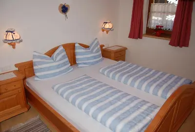 a bed with blue and white pillows on it at Vilahof in San Vigilio Di Marebbe